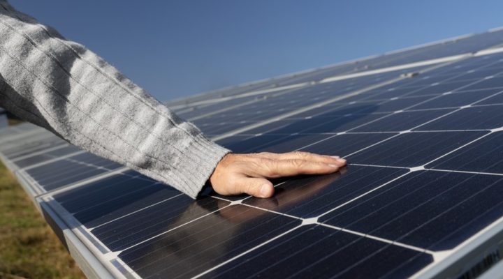 Na zdjęciu ktoś sprawdza żywotność paneli fotowoltaicznych wizualnie.